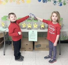 Pictured are Kindergarteners Tanner Bernice from Mrs. Lawrence's class and Julianna Stefanelli from Ms. Roy's class placing their donations in the canisters belonging to each of their classes.