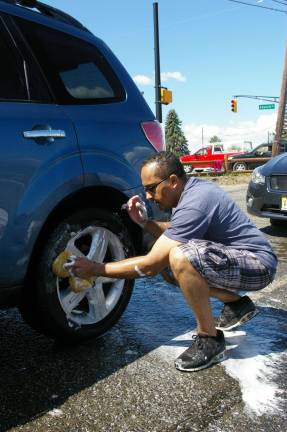 Church group holds car wash fundraiser Team Leader Sam Perez scrubs the wheels and tires.