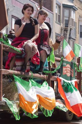 Members of Wild West City in Byram sit on a fencepost on a float.