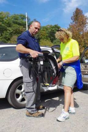 Newton Police Sergeant Dean Coppolella and Northern New Jersey Safe Kids Senior Checker Jackie Stackhouse make adjustments to a child car safety seat.