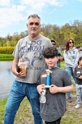 Lucas Fish holds the trophy that he won for catching the largest fish at the derby. With him is his father, Rob.