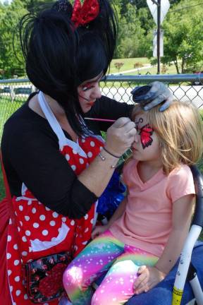 Dakota Inks, 5, has a butterfly painted on the face by Kerry Tobin of Highland Lakes. She is better known as Pixie Pop the Clown.