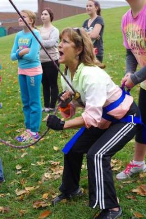 Health and physical education teacher Michelle Gagg is shown belaying a student suspended in the air high above her.