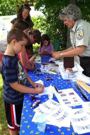 U.S. Fish &amp; Wildlife Service employee Fran Stephenson helps the children make dragonflies and beetles.