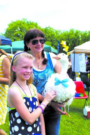 Katherine Webbe, 10, of Vernon poses with Oliver the goose as Barry Lakes author Leesa Beckmann looks on. The Sebastopol goose is a recurring favorite at town events.