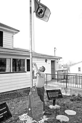 Photo by Chris Wyman Bob Constantine raises the flags in front of the VFW Post.