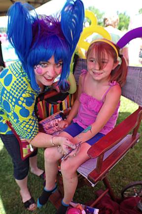 Cristina Moscatelli, 6, of Highland Lakes gets a painted tattoo by artist Terry Tobin, also of Highland Lakes.