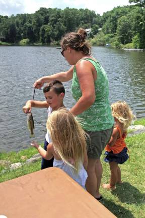 Erin LaPort helps her son Anthony, 6, with another fish that he reeled in during the contest.