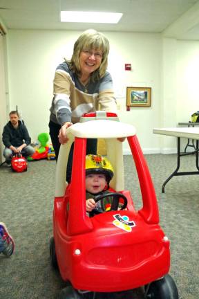 Footprints Montessori School director Mrs. Bjorg Boschen helps one of the youngest racers make his way around the racecourse.