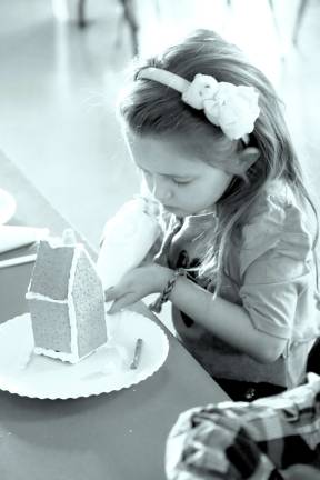 Church holds Christmas craft event Jazmin Houghtaling of Sussex adds a touch of icing as glue for the candy decorations going onto her gingerbread house.