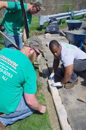 Volunteers beautify PAL building Project coordinator Jay Meerendonk of Countryside Landscaping (left) and Alastair Williams of New Magic Landscaping check the alignment of the paving stones.