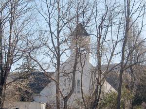 The steeple of the former St. Thomas Church looms through the trees.
