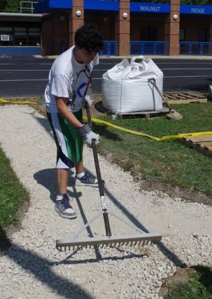 Dominic D'Arco, a Vernon Township High School senior, is shown raking the base for the flagpole area paving project at Walnut Ridge Primary School during the school&#xfe;&#xc4;&#xf4;s Fall Harvest Open House on Saturday.