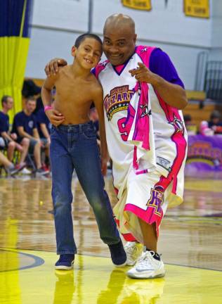 Harlem Wizard Arnold &quot;A-Train&quot; Bernard is shown with Daniel Arroyo, 8, of Vernon who made a basket for the Wizards and was then awarded with an official jersey during the team&#xfe;&#xc4;&#xf4;s bout with Vernon firefighters. &#xfe;&#xc4;&#xa2; Vernon firefighters take on the Harlem Wizards