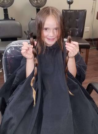 Amilya Abbot shows off the hair she had cut off.