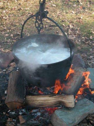 Steam rises as sap from sugar maple trees is boiled down in an iron pot to make maple syrup at Millbrook Village (Photo provided)