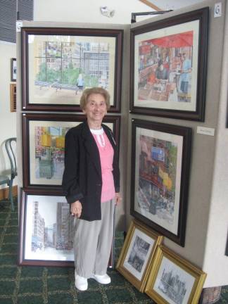 Mary Ann Mastrangelo, chairperson of the show, poses with Highland Lakes artist Bruce Young&#x2019;s scenes of NYC.