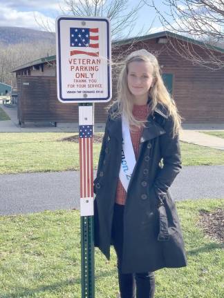 Hannah Van Blarcom stands with a Veterans Parking Only sign.