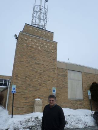 Anthony Selimo, founder of the Sussex County Community College radio station, stands in front of the E building where the radio station's two antennas stand. The taller one, at 49 feet, will broadcast the FM signal. Photo by Nathan Mayberg.