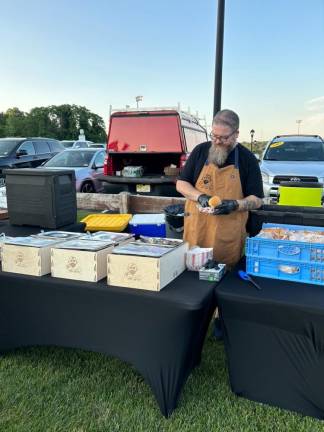 Brian Hochstaedt of the Bearded Baby Que makes a pulled pork sandwich at the event.