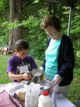 Historical Society Trustee Shirley Baldwin helps a child mix dough to make biscuits.