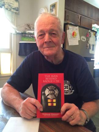 Photo by Laurie Gordon Tom Cooney sits proudly wearing his F.D.N.Y. Harlem Ladder Compay #30 shirt and holds the book he wrote about his experiences on the force entitled The Man Behind Badge #711