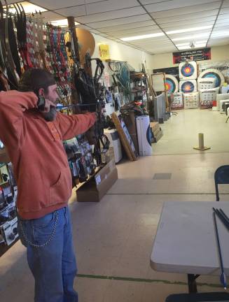 Mountain Mike's owner Mike Bush demonstrates shooting a bow-and-arrow at his shope in the McAfee section of Vernon.