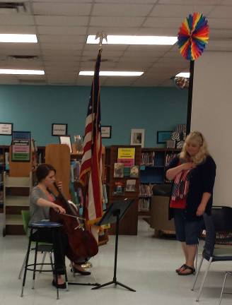 Victoria Meneses of the Vernon Township High School Orchestra, playing the cello at the Board of education meeting in honor of Flag Day, as school board vice president Cynthia Auberger looks on. Meneses, who is going into her senior year and plans to follow a career in music education, played &quot;Amazing Grace&quot;, &quot;This Old Flag&quot; and &quot;The Star Spangled Banner&quot;.