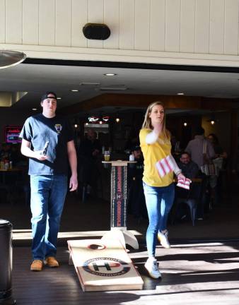 CR2 Lisa Ball of Vernon tosses a bag in the cornhole tournament Saturday, Feb. 3 at Hef’s Hut Bar and Grill. At left is Tim Boonstra of Oak Ridge.