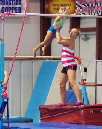 Instructor Jacqueline Combs works with an athlete on the uneven bars.