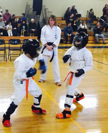 Jackson Saltzman prepares to try and score a point while Michael Struble gets ready to counter during sparring competition. Judging the match is Sensei Monica Rolando