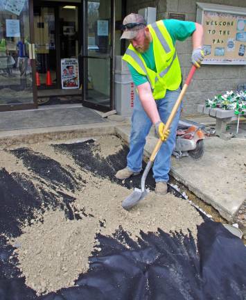 Project coordinator Jay Meerendonk of Countryside Landscaping spreads the next layer of sand before the PAL building&#xfe;&#xc4;&#xf4;s front walkway is replaced.
