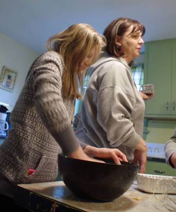 At left, Hannah Van Blarcom, 13, mixes the ingredients for banana bread the old fashioned way, by hand. Behind her directing the assembly line is church youth group leader Davida Schnebelen.