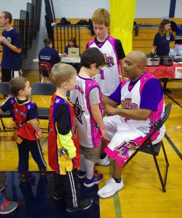 Harlem Wizard Arnold &quot;A-Train&quot; Bernard signed jerseys and then posed with some of the visiting children.