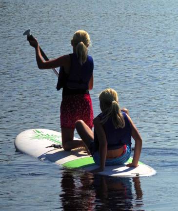 Two young girls head out onto Wawayanda Lake on a paddle board. The park&#xfe;&#xc4;&#xf4;s beach is now closed to swimming but boat rentals are still available.