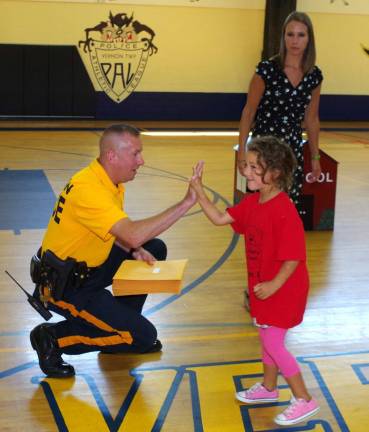 Vernon Township Police Department Corporal Scott Waleck greets Piper Arnold, 5, of Highland Lakes with a high five. Arnold was the first of 31 children to be called out to receive their Safety Town graduation certificate. In the background is teacher Lisa Haw.