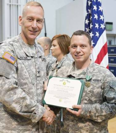 Col. Timothy Holtan, commander and conductor of The U.S. Army Field Band, presents Staff Sgt. Jared Morgan, media producer, the Army Commendation Medal on Aug. 12 during a ceremony at Fort George G. Meade, Maryland.