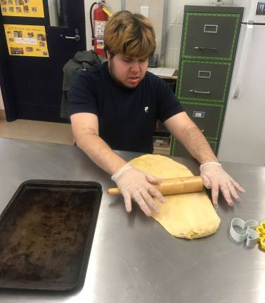 Dominick Shamble rolls out the dough for the biscuit cutting process.