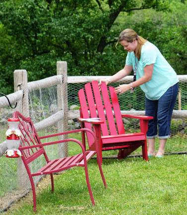 PHOTOS BY VERA OLINSKI Kristie Lyons places the new red chair in the corner of the garden.