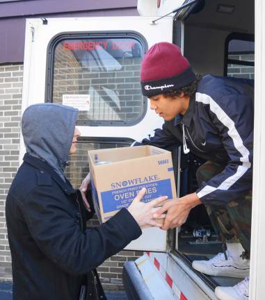 Students load boxes of food in the bus.