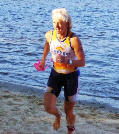 Triathlete Tracey Swenson of Sparta Township runs onto the beach from the water after finishing swimming during the triathlon. Swenson finished in 28th place overall with a time of 1:13:54. She also finished first in the female 50-54 age category with the time of 1:13:54.56.