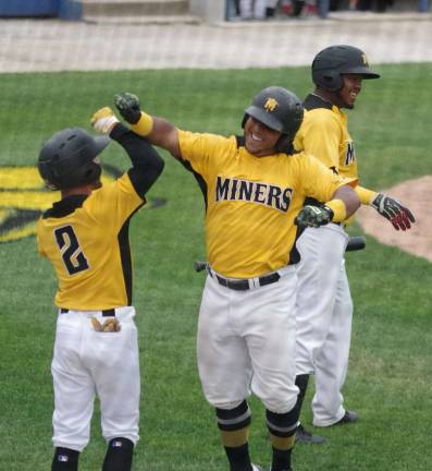After crossing home plate after hitting a home run in the fourth inning Sussex County Miner Martin Figueroa (center) celebrates with teammates.
