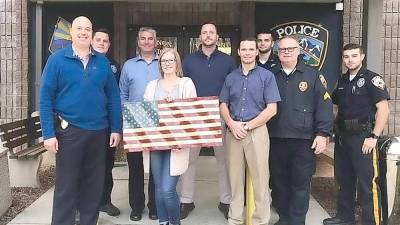 Kimberly Rudy is shown presenting the flag carved by her fiance, A.J. Commaroto to members of the Vernon Townshp Police Dept.