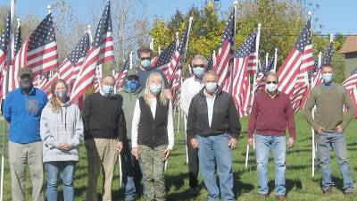 Volunteers complete the task of flag placement and pose for a photo on a crisp autumn Saturday (Photo by Janet Redyke)