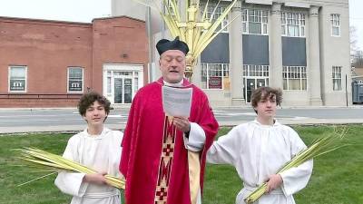 Father Robert Griner delivers the Liturgy of the Palms on the Newton Green with his sons Jesse and Elliott serving as acolytes.