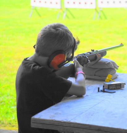 A young man shoots rifle at the Falling Plates targets.