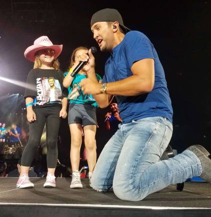 Bella Valerius, left, is on stage with Luke Bryan, right.
