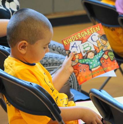 Future kindergartners introduced to school PHOTOS BY VERA OLINSKI A student examines his new book.