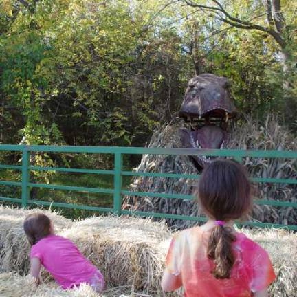 A tyrannosaurus rex surprises two young girls during their hayride.