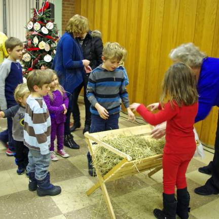 Children place hay in the manger.
